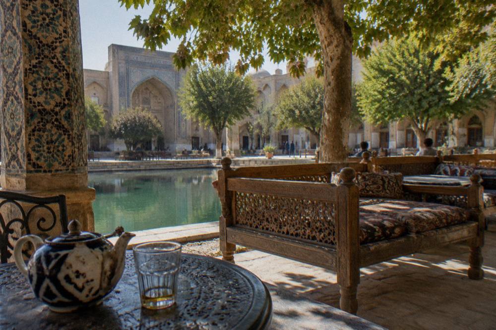 A hotel courtyard with patterned tiled columns and wooden benches in warm afternoon light