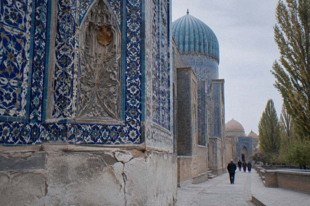 A blue domed madrasah facade with intricate tilework under a clear sky
