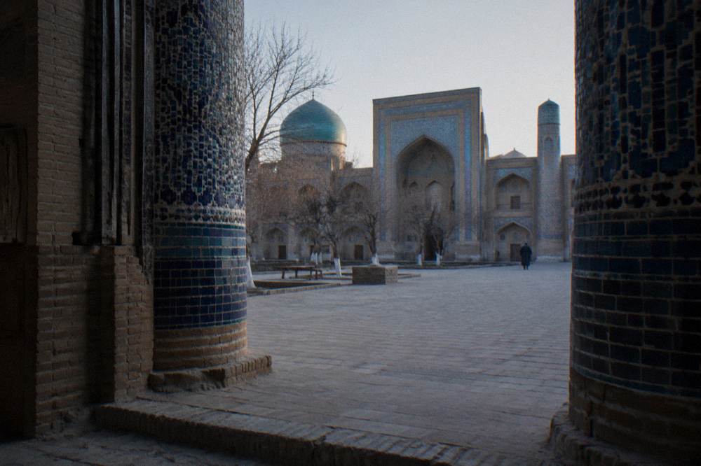 A courtyard of a medieval madrasah with intricate tiled walls and a quiet passageway