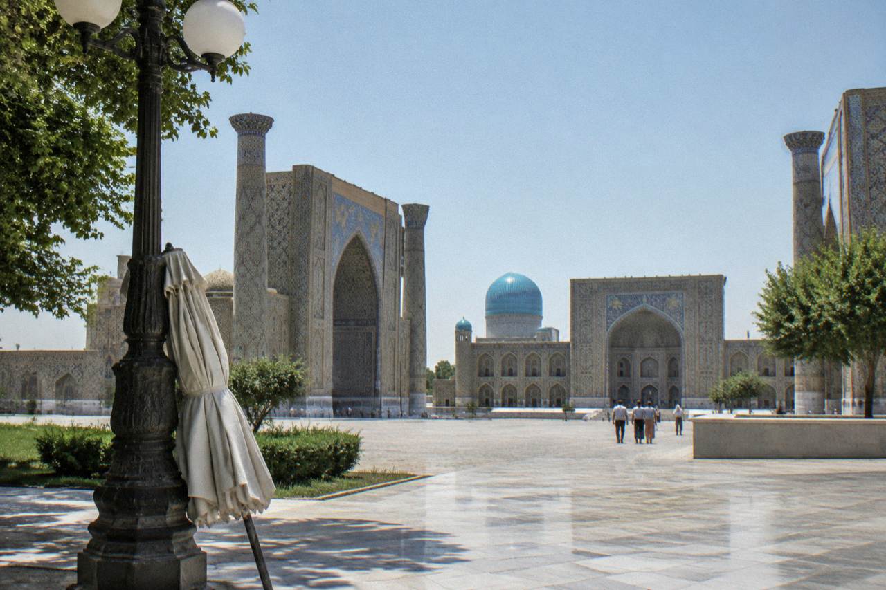 Blue tiled domes and minarets of a Silk Road city skyline under a clear sky