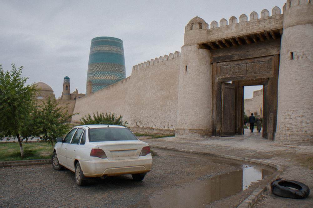 Private car parked outside the gate of a walled old town in Uzbekistan