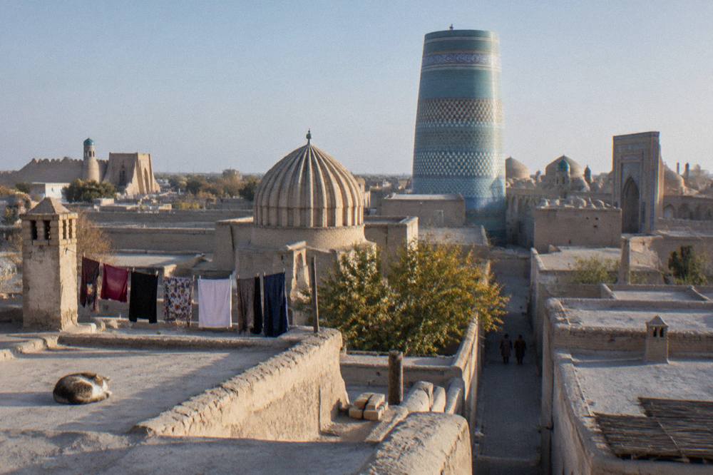 Blue tiled dome and minaret rising above an old city street in Uzbekistan