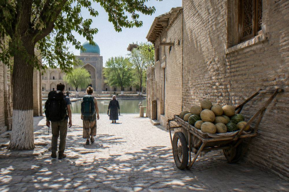 Travelers walking with backpacks through a sunlit old town lane flanked by mud brick walls