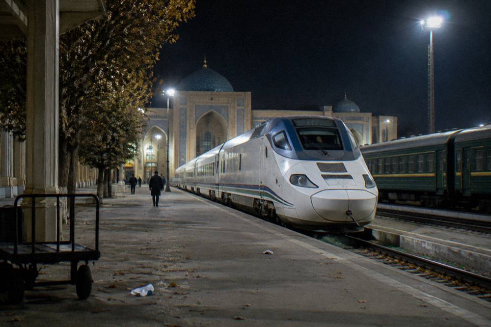A fast passenger train standing at a station platform in Uzbekistan