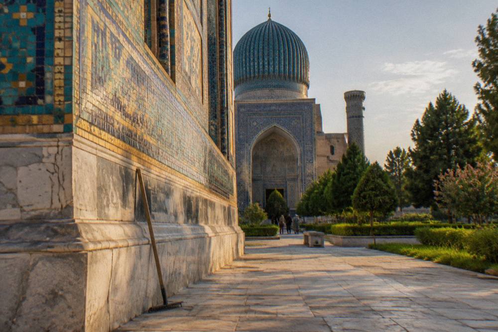 Ornate tiled wall of a Samarkand monument glowing under strong afternoon sunlight
