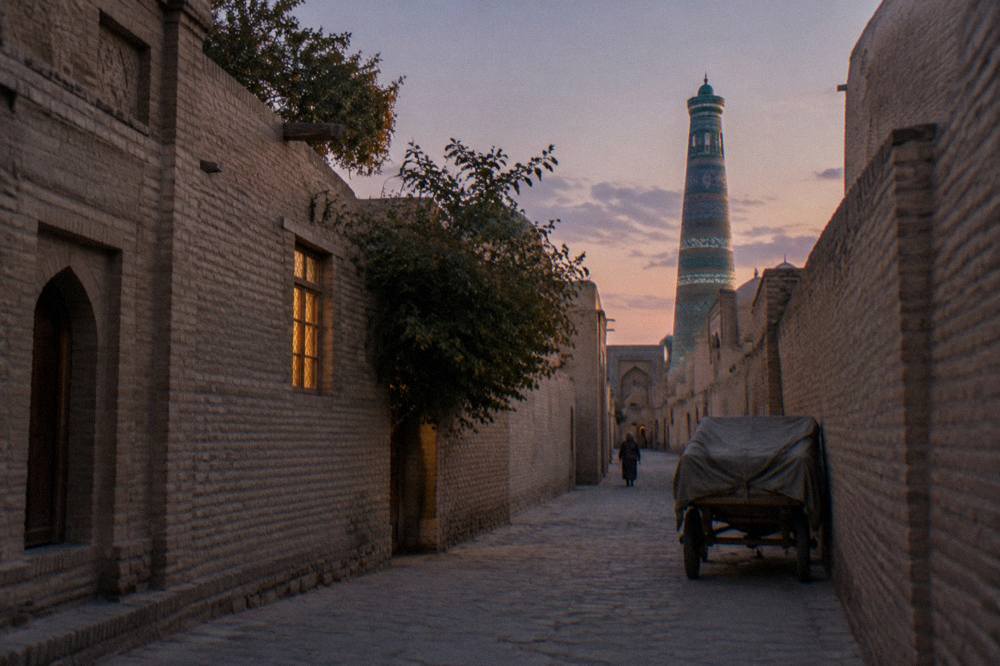 Turquoise tiled minaret and mud brick wall rising above narrow lanes of an old walled city