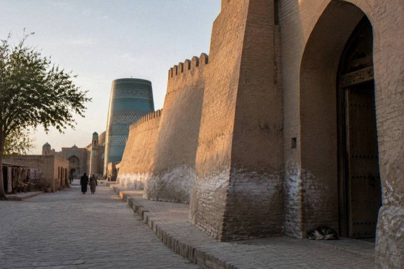 Ancient mud-brick walls, watchtowers and minarets of Itchan Kala rising over Khiva at sunset