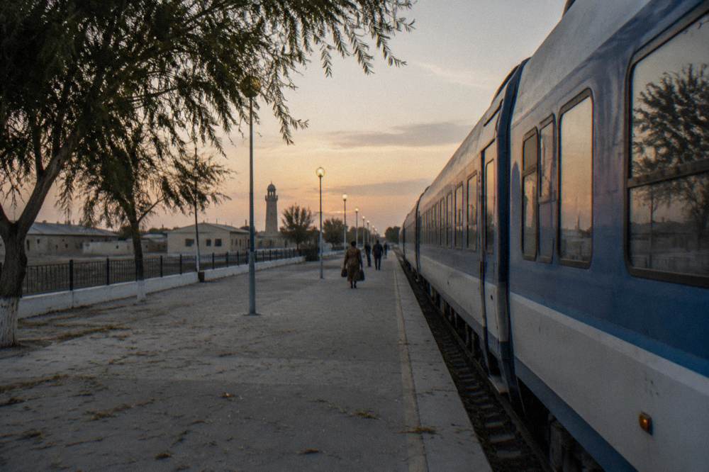 Modern high-speed train standing at a station platform beside a desert town