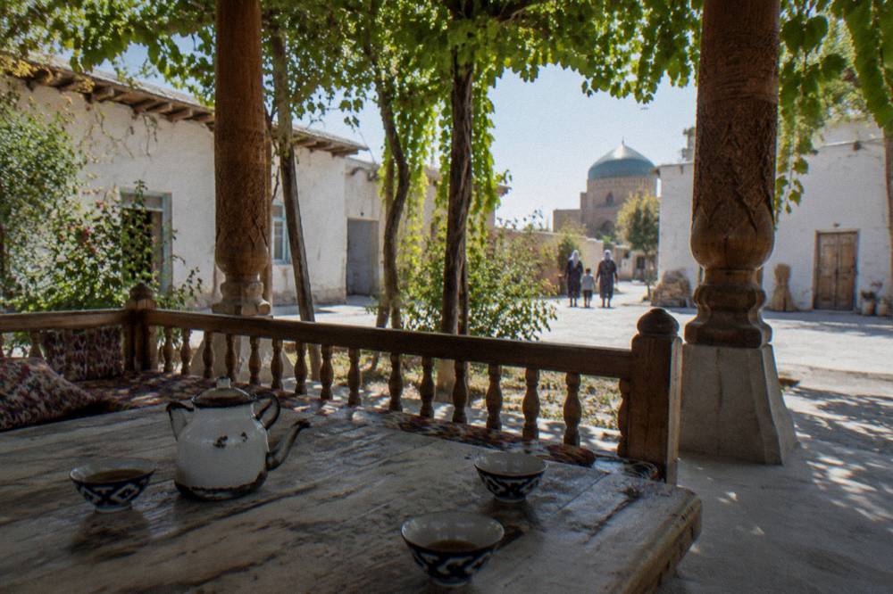 Courtyard guesthouse with carved wooden columns and a shaded seating platform