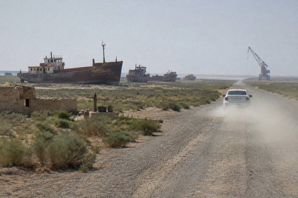 A private tour vehicle parked on a desert road beside open flat steppe land under a wide sky