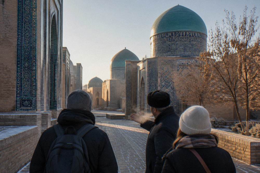 A guide speaking to visitors in a courtyard of tiled medieval mausoleums with turquoise domes above