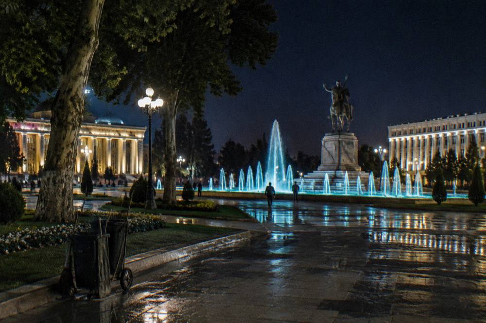 A modern city square with fountains and government buildings under a clear evening sky