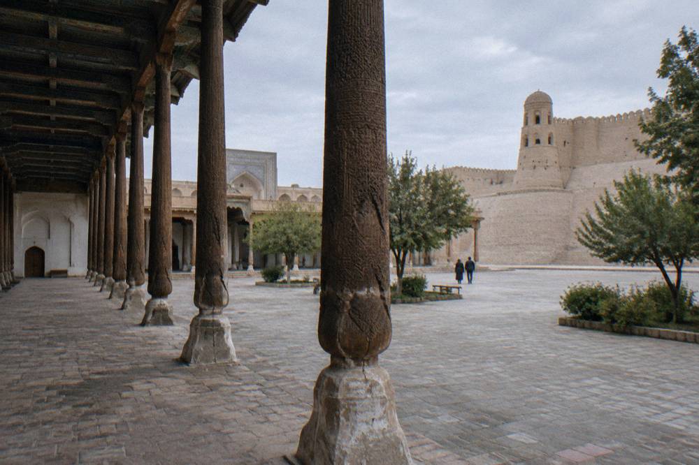 Carved wooden pillars of a madrasah courtyard with intricate painted ceilings