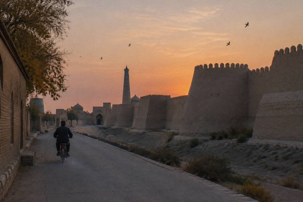 Ancient walled city skyline with mud brick ramparts and a minaret at dusk