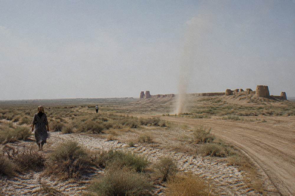 Desert fortress ruins on a plain with distant mud brick walls under a wide sky