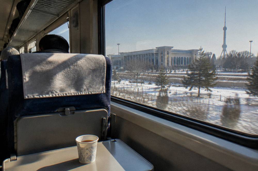 Interior of a modern high-speed train with seats and luggage racks in daylight