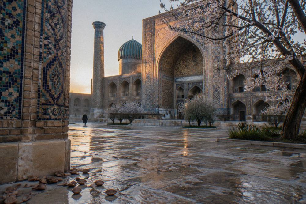 Sunlit tiled courtyard of a medieval Silk Road monument with intricate blue mosaics