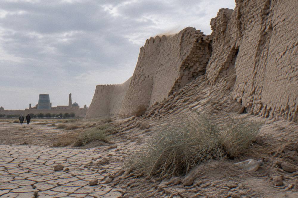 Ancient mud brick fortress walls rising from open desert under a wide sky