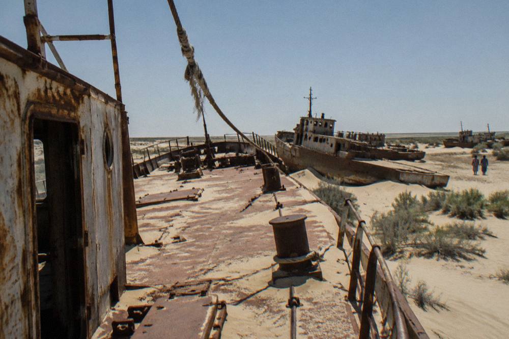 Rusting ship hulls half buried in sand at a dry harbor in the desert