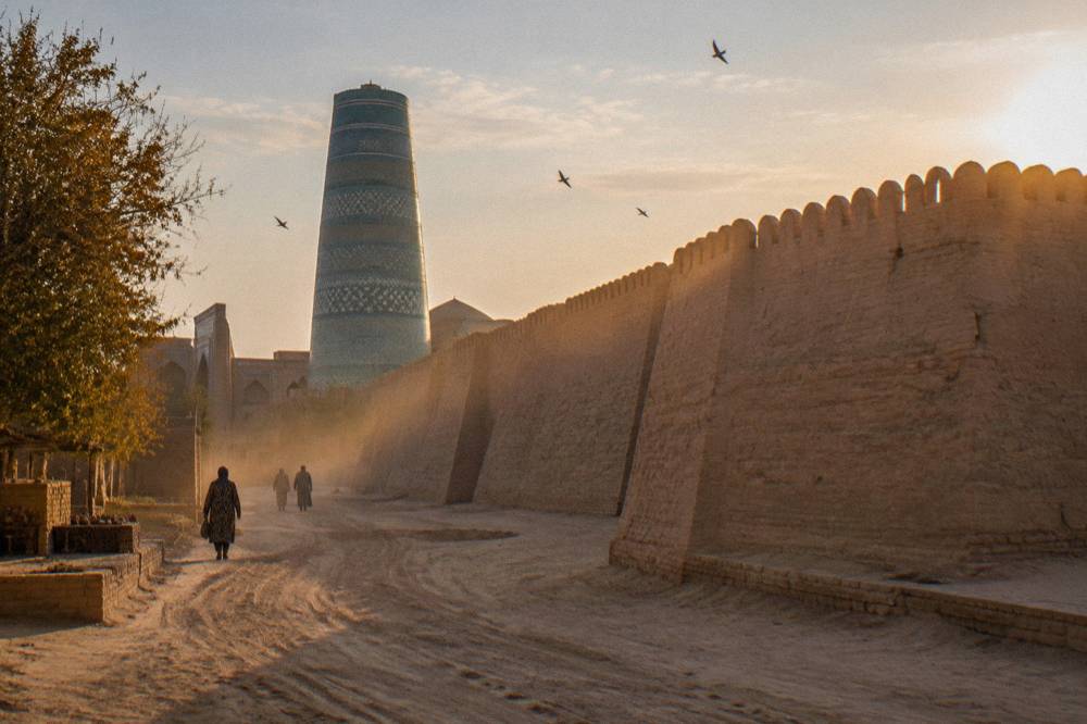 Walled old town with mud brick ramparts and a tall minaret at golden hour
