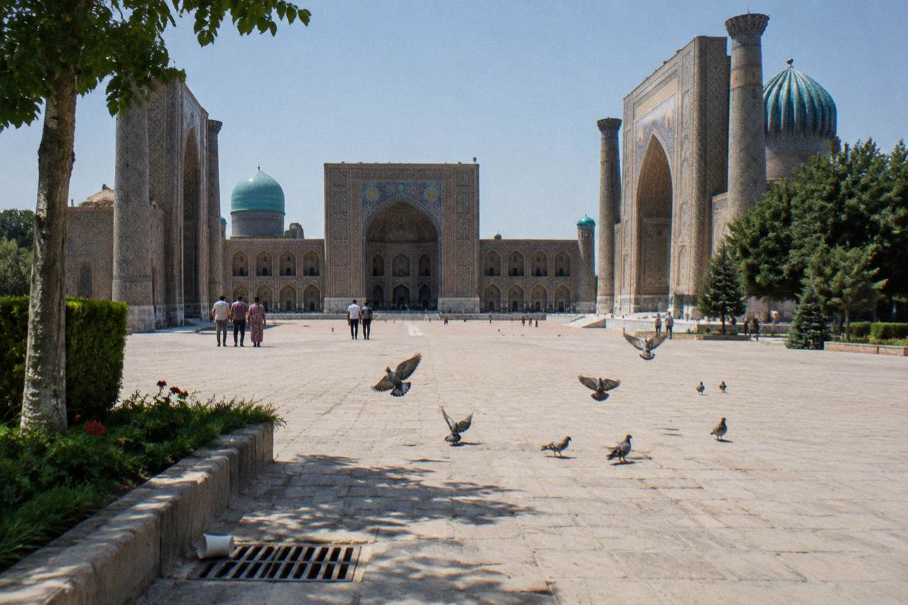 Blue tiled domes and minarets of a historic Silk Road city under a clear sky
