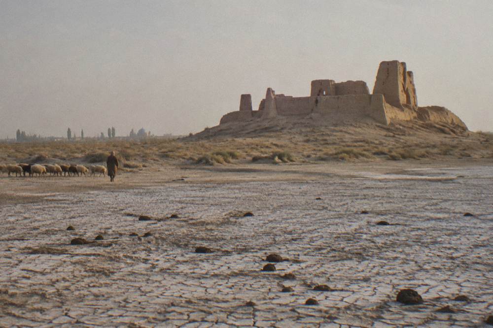 Ancient mud brick fortress walls rising from open desert steppe