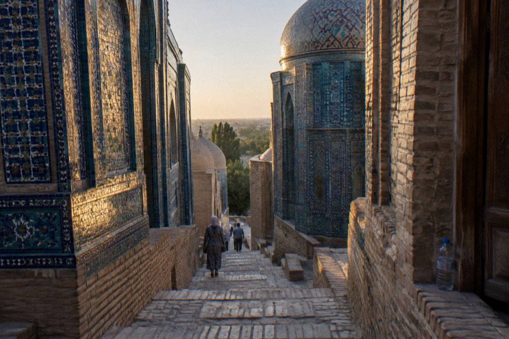Long tiled corridor of blue mausoleums glowing in morning light