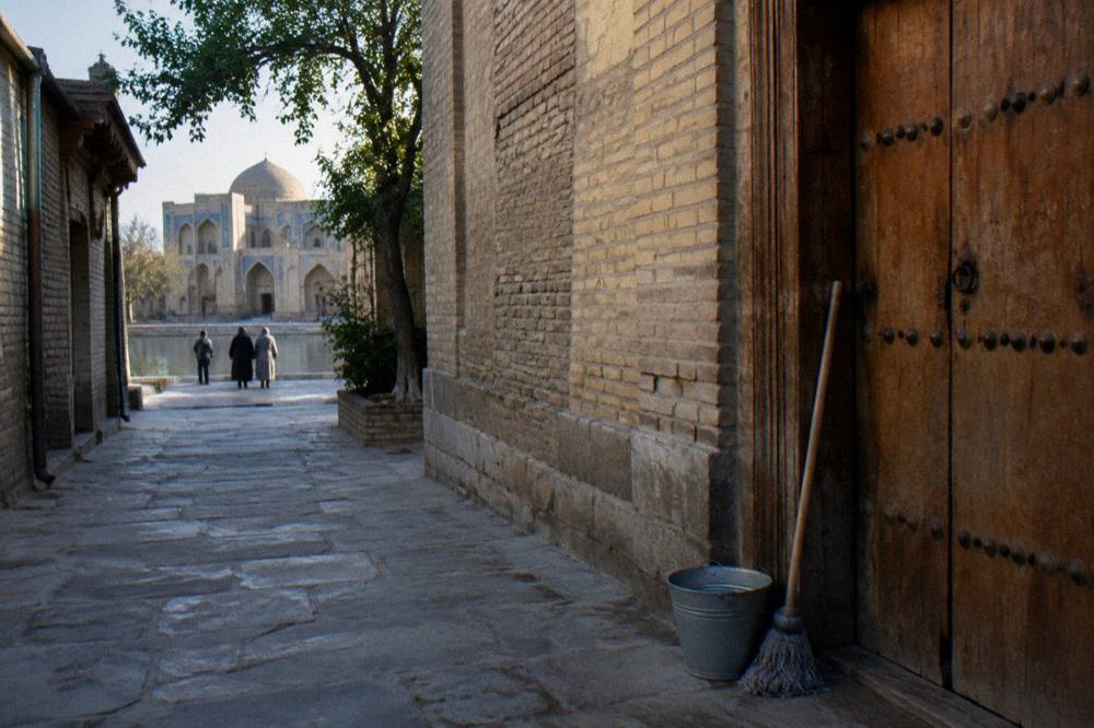 Narrow stone street in the Bukhara old town with restored madrasah walls