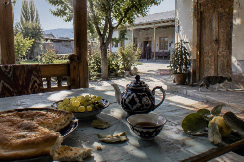 Breakfast table set with bread, fruit and tea in a courtyard guesthouse
